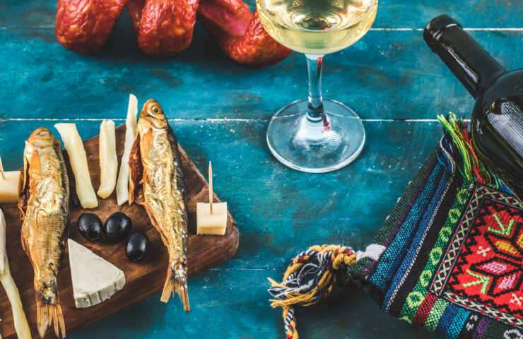 Cheese sticks with smoked fish on blue background with a glass of wine