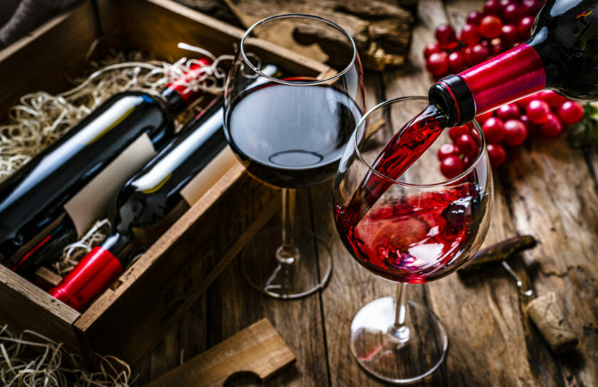 Pouring red wine into a glass on rustic wooden table